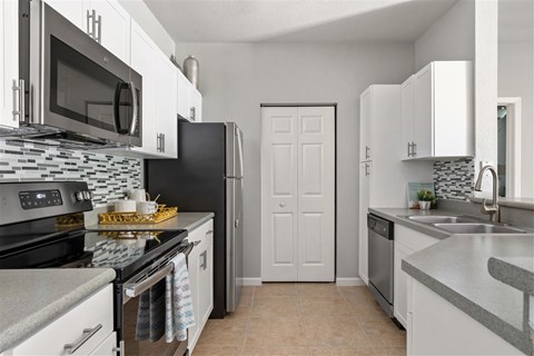 A kitchen with white cabinets and a black refrigerator.