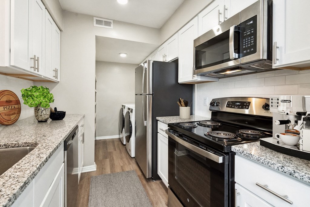 a kitchen with white cabinetry and black appliances  at Lake Johnson Mews, Raleigh