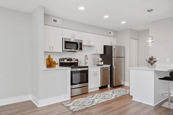 A kitchen with white cabinets and a black chair.