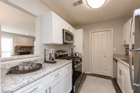 a kitchen with white cabinets and granite counter tops