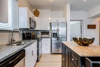 a kitchen with white cabinets and black countertopsat East 51 At Rocketts Landing, Richmond, VA