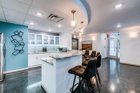 a kitchen with a bar and chairs in front of a counter