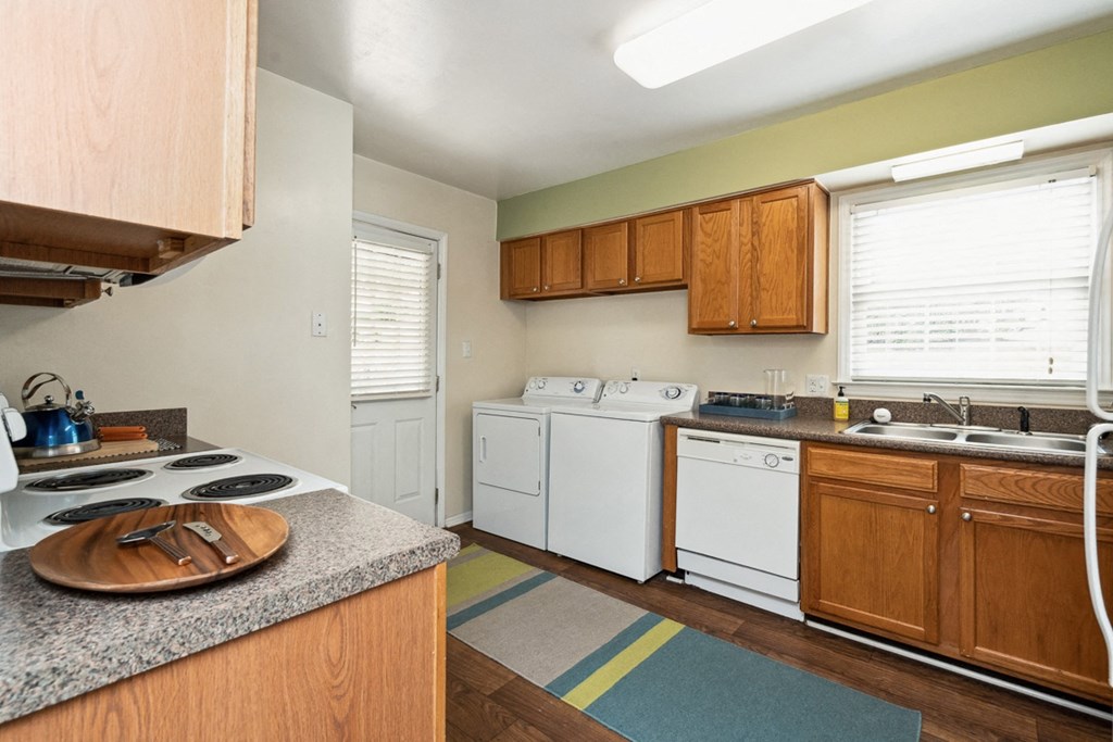a kitchen with white appliances and wooden cabinets  at Lake Johnson Mews, North Carolina, 27606