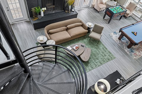 A living room with a pool table and a spiral staircase.