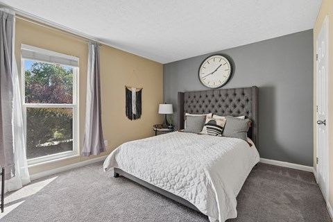 A bedroom with a large bed and a window with curtains.