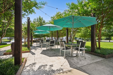 A patio with tables and chairs under green umbrellas.
