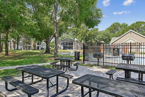 A black picnic table and bench are in a park.