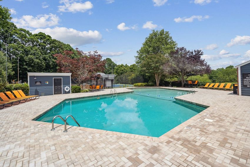 a swimming pool with lounge chairs and trees in the background