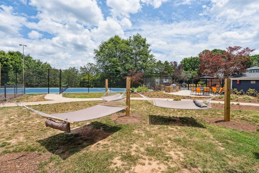 a backyard with two hammocks and a playground in the background