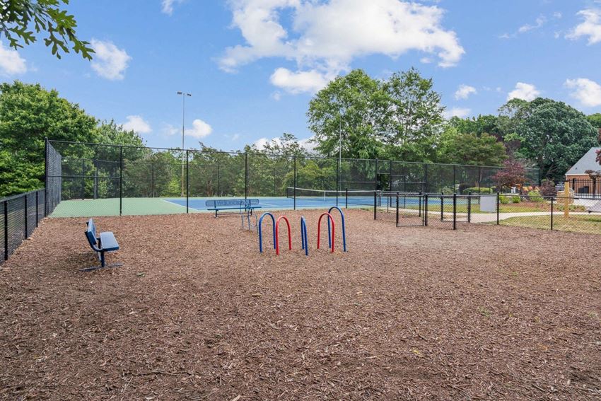 a park with a bench and a bench in front of a tennis court