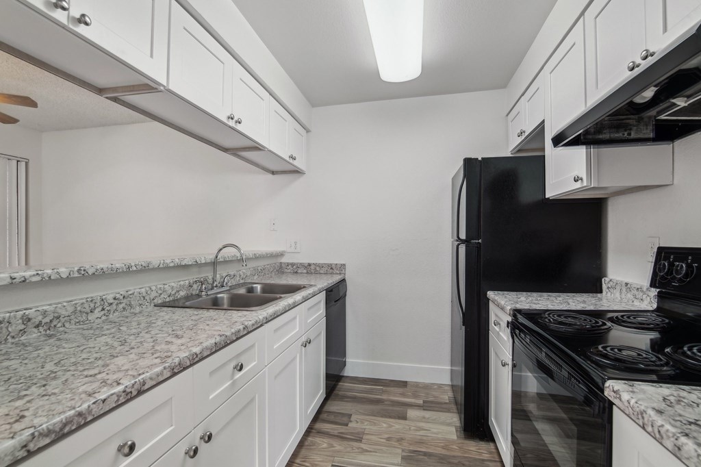 A kitchen with a black refrigerator and white cabinets at Candela Park Apartments, Arizona, 85201