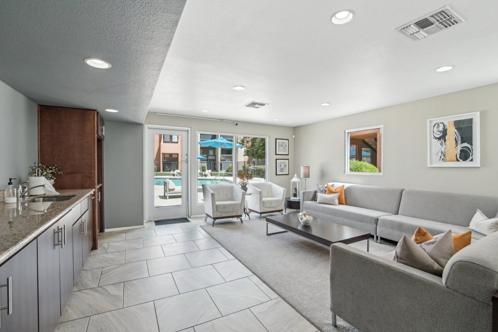 A modern living room with a grey couch and a kitchen area with a sink at Candela Park Apartments, Mesa, AZ, 85201