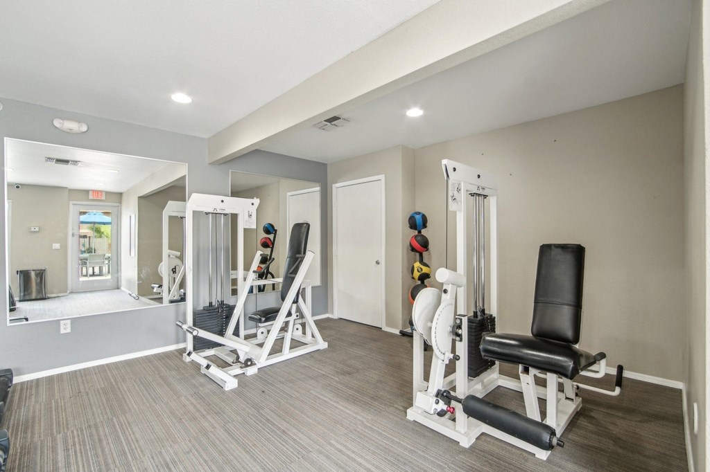 A well-equipped home gym with a variety of exercise machines at Candela Park Apartments, Mesa