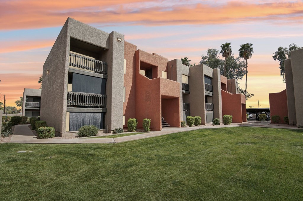 A modern building with a green lawn in front at Candela Park Apartments, Mesa
