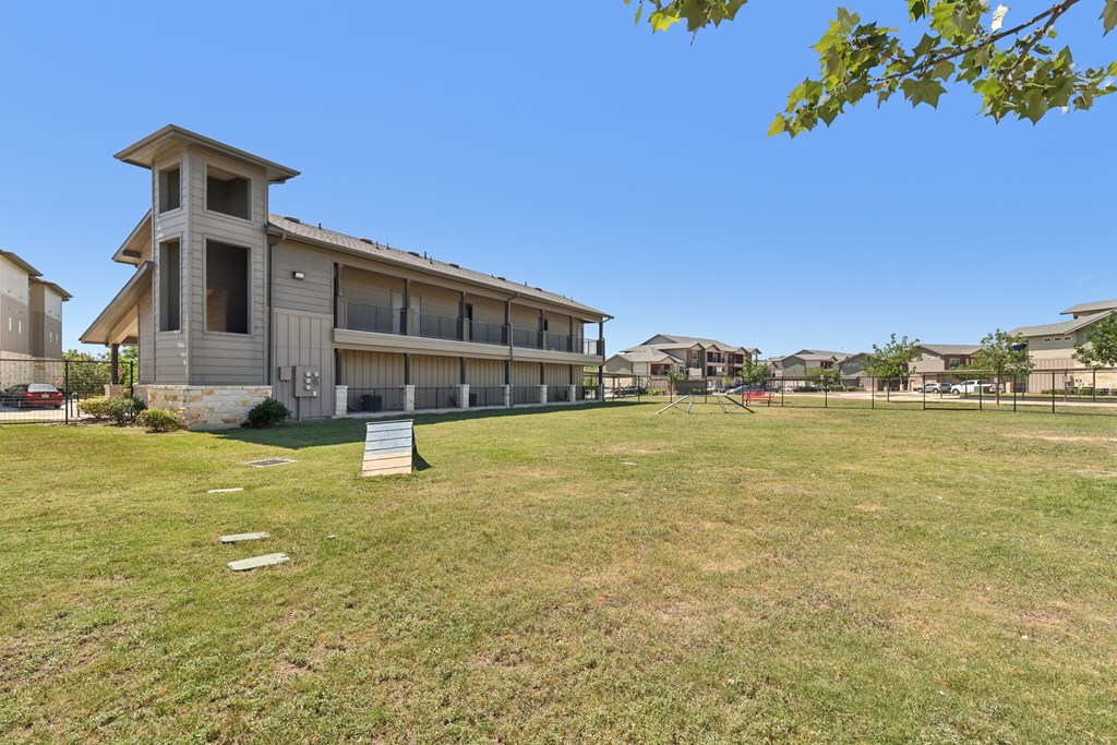 A grassy field with a building and a sign in the foreground.