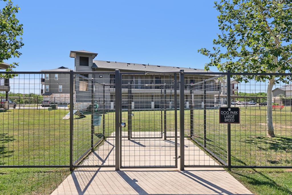 A black metal gate with a sign that reads "DOG PARK BREAK" in front of a building.