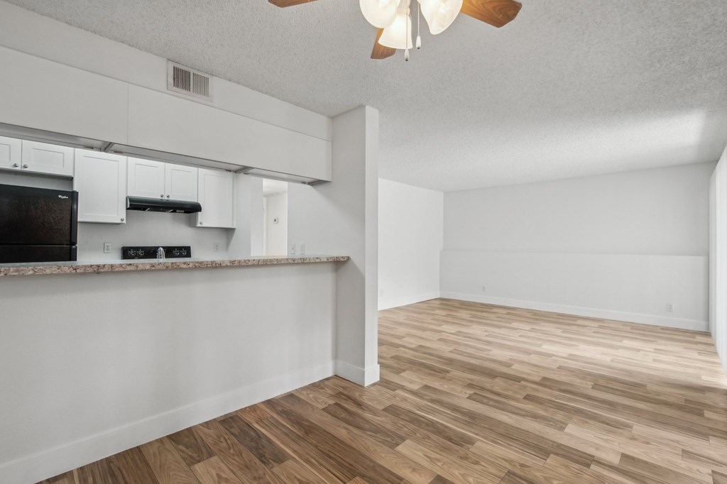 A kitchen with white cabinets and a black fridge at Candela Park Apartments, Mesa, Arizona