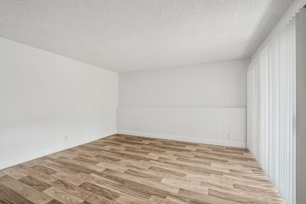 A room with wooden flooring and white walls at Candela Park Apartments, Mesa 85201