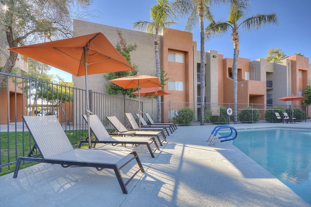 A poolside area with sun loungers and umbrellas at Candela Park Apartments, Arizona