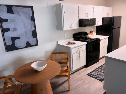 a kitchen with white cabinets and black appliances and a small table