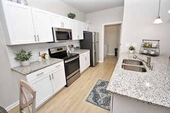 Model Kitchen with hard floors, an island, granite counters, and stainless steel appliances - Photo Gallery 4