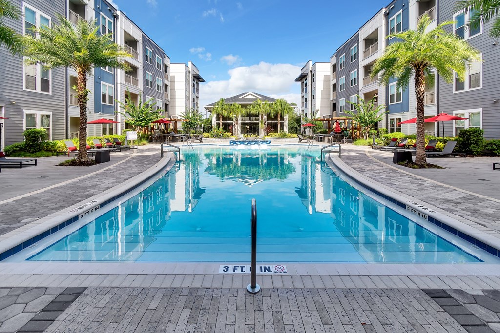 a swimming pool with a gazebo and palm trees in front of an apartment building
