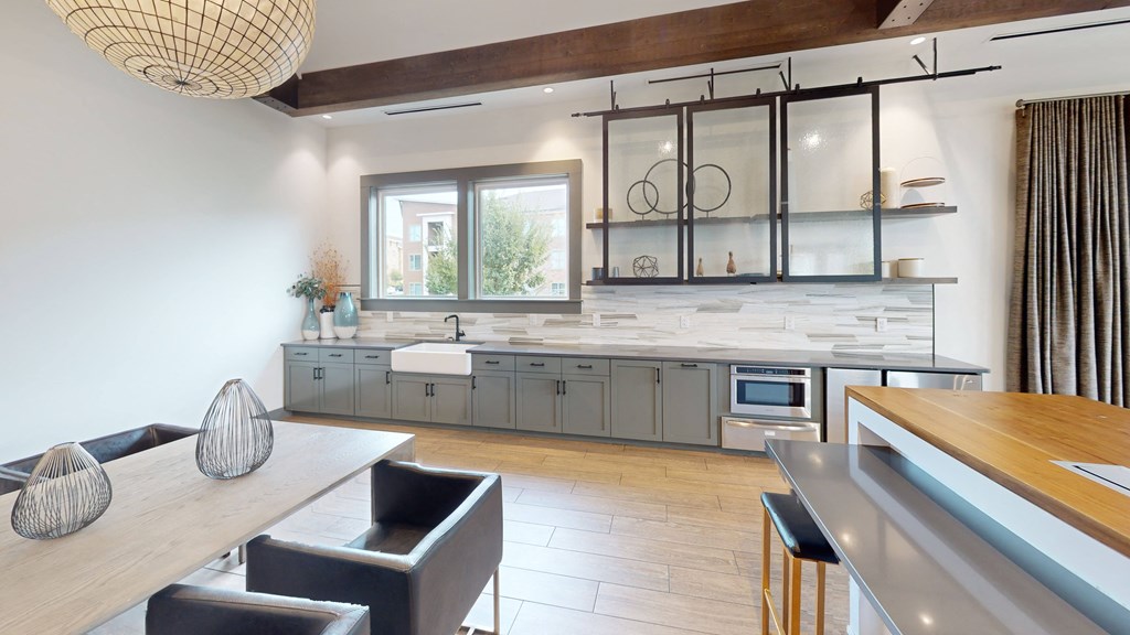 a clubhouse kitchen with gray cabinets and a table and chairs