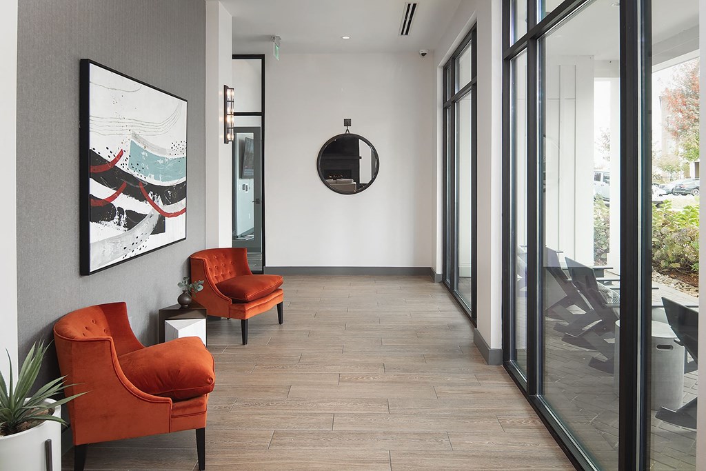 a hallway with two orange chairs and a mirror on the wall