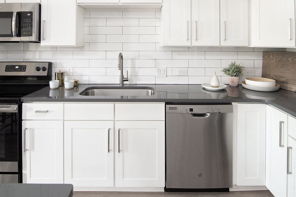 a kitchen with white cabinets and a stainless steel dishwasher