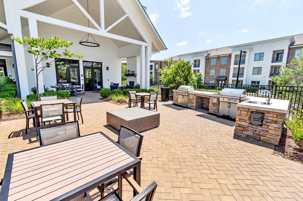 a patio with tables and chairs and a grill and a building