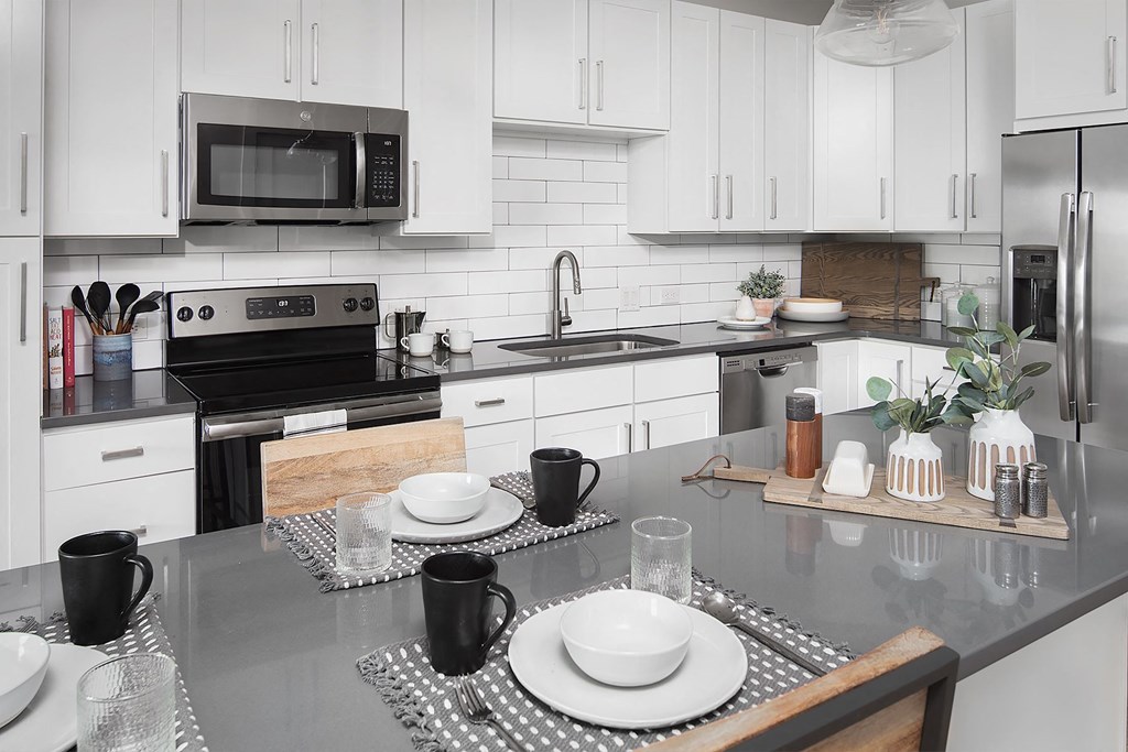 a kitchen with white cabinets and black counter tops