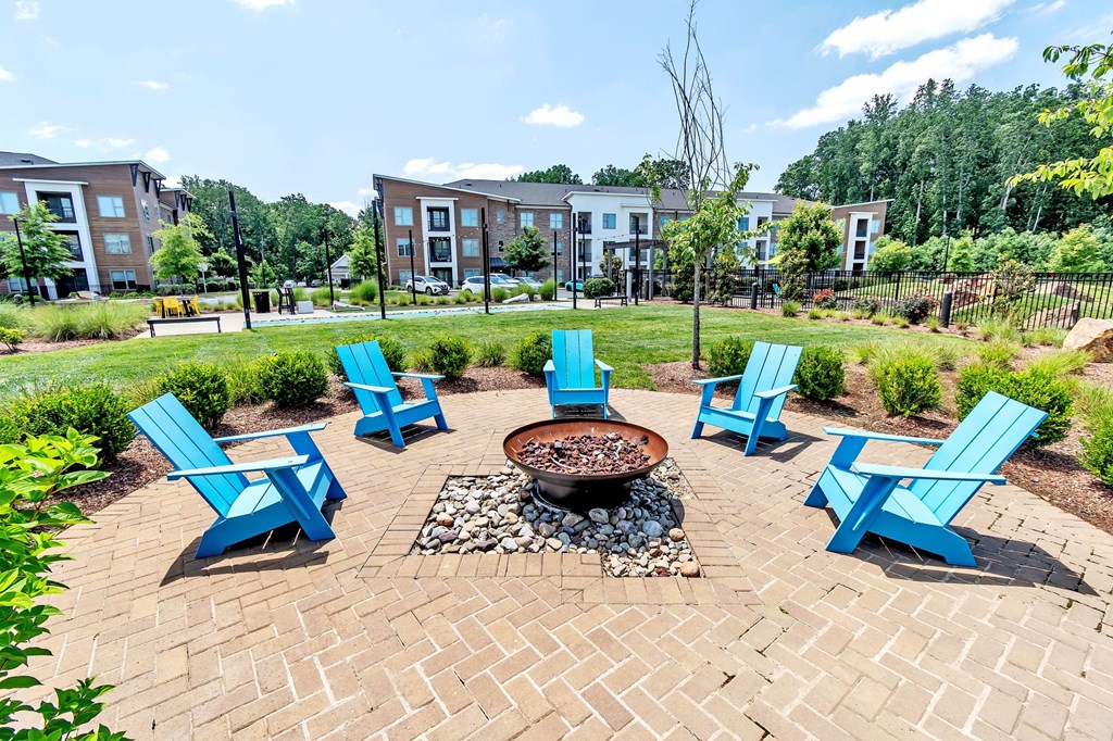 an outdoor seating area with blue chairs and a fire pit