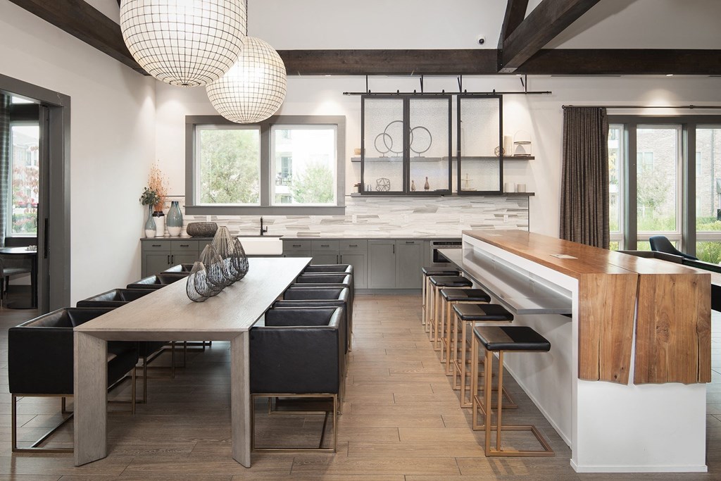 a clubhouse with a long wooden table and chairs and a kitchen with a bar