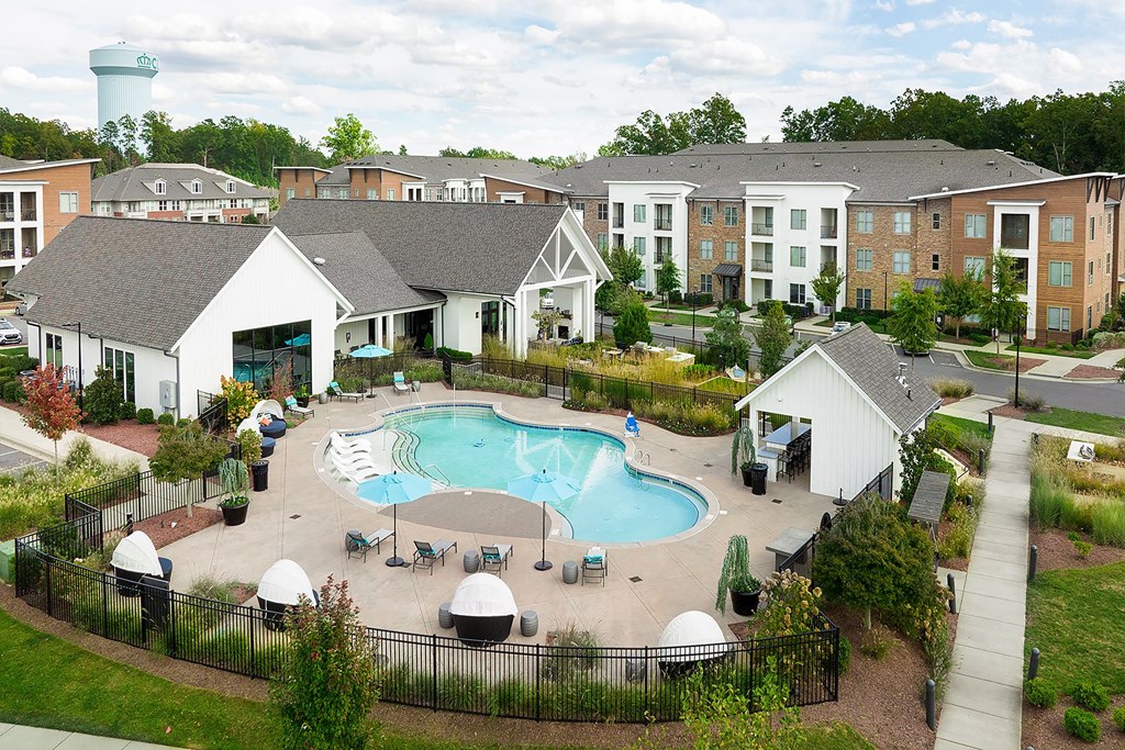 an aerial view of an outdoor pool with apartments in the background