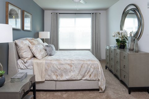 A bedroom with a bed, dresser, and mirror.
