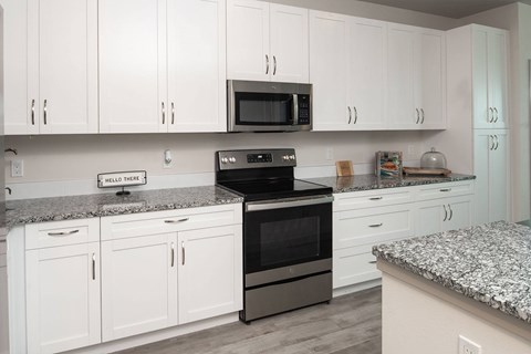 A kitchen with white cabinets and a granite countertop.