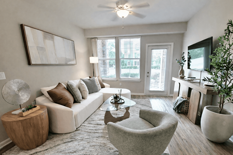 A living room with a white couch, a grey armchair, a wooden side table, and a large painting on the wall.