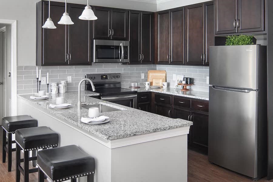 a kitchen with a marble counter top and a stainless steel refrigerator