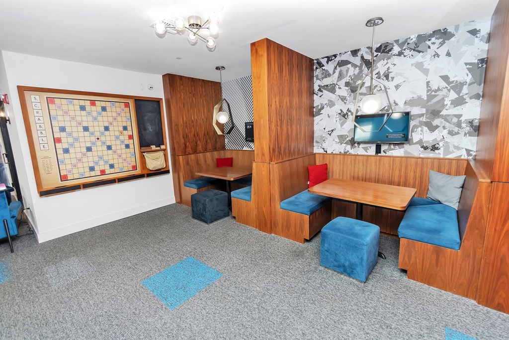 a seating area with two tables with blue chairs and two blue chairs with red cushions