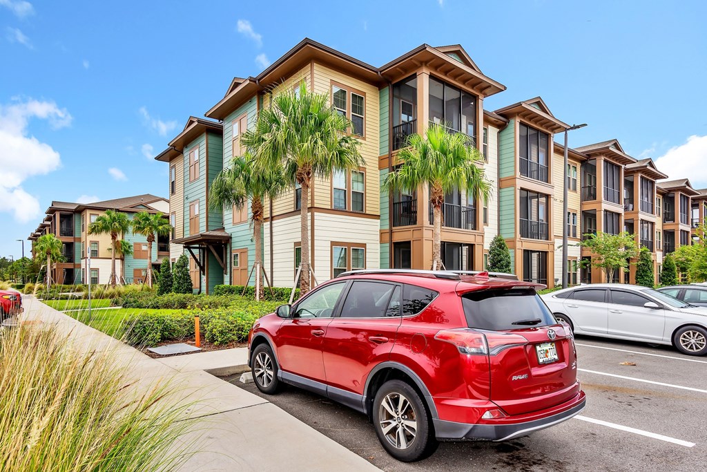 a red car parked in front of an apartment complex