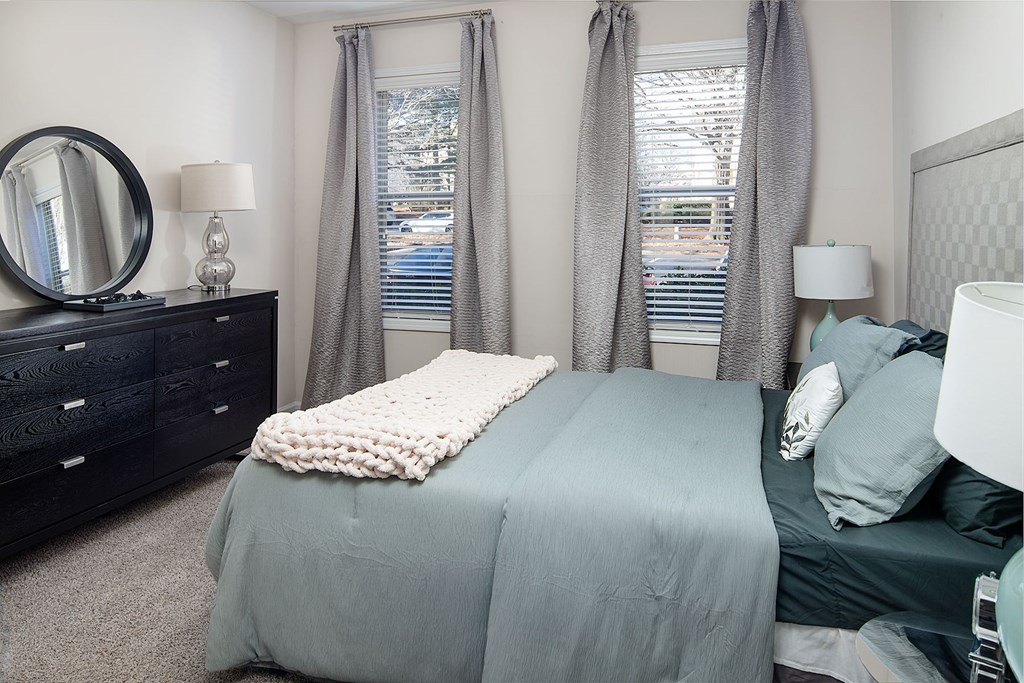 A bedroom with a bed, nightstand, and window.