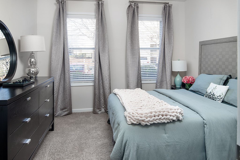 A bedroom with a large bed and a dresser with a mirror.