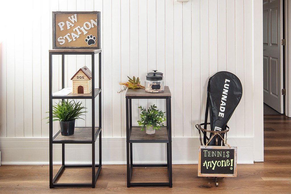 A small shelf with a sign that says "Paw Station" and a sign that says "Tennis anyone?" is next to a chair with a "Luncheon" sign on it.