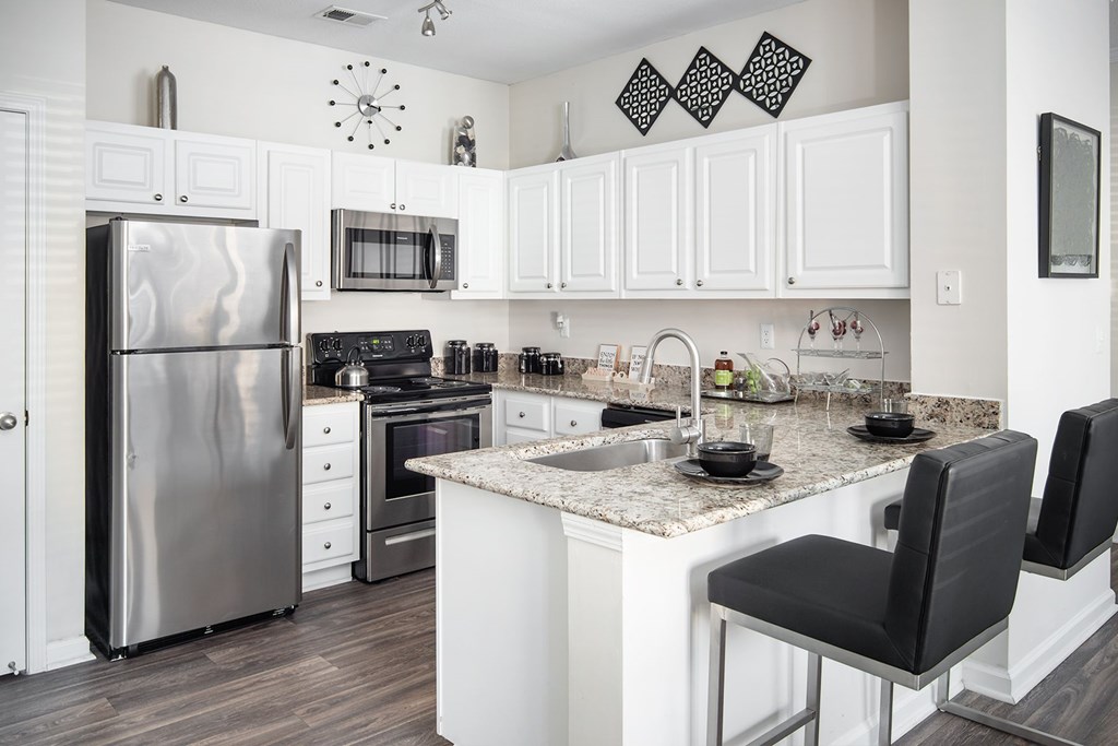 A kitchen with a refrigerator, oven, and sink.