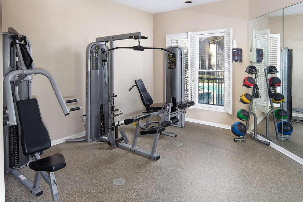 A home gym with a mirror, weights, and exercise equipment.