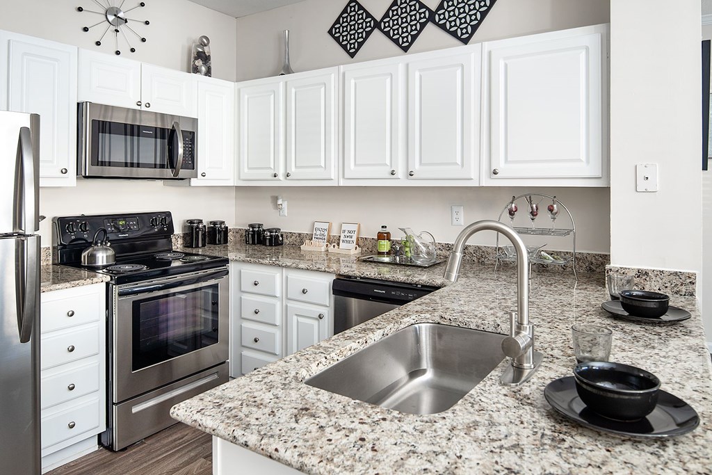 A kitchen with a granite countertop and stainless steel appliances.