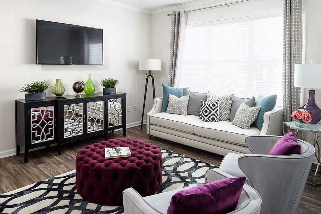 A living room with a white couch and a red ottoman.