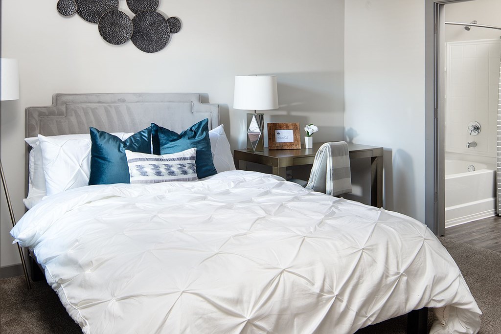 A bed with a white comforter and blue and white pillows.