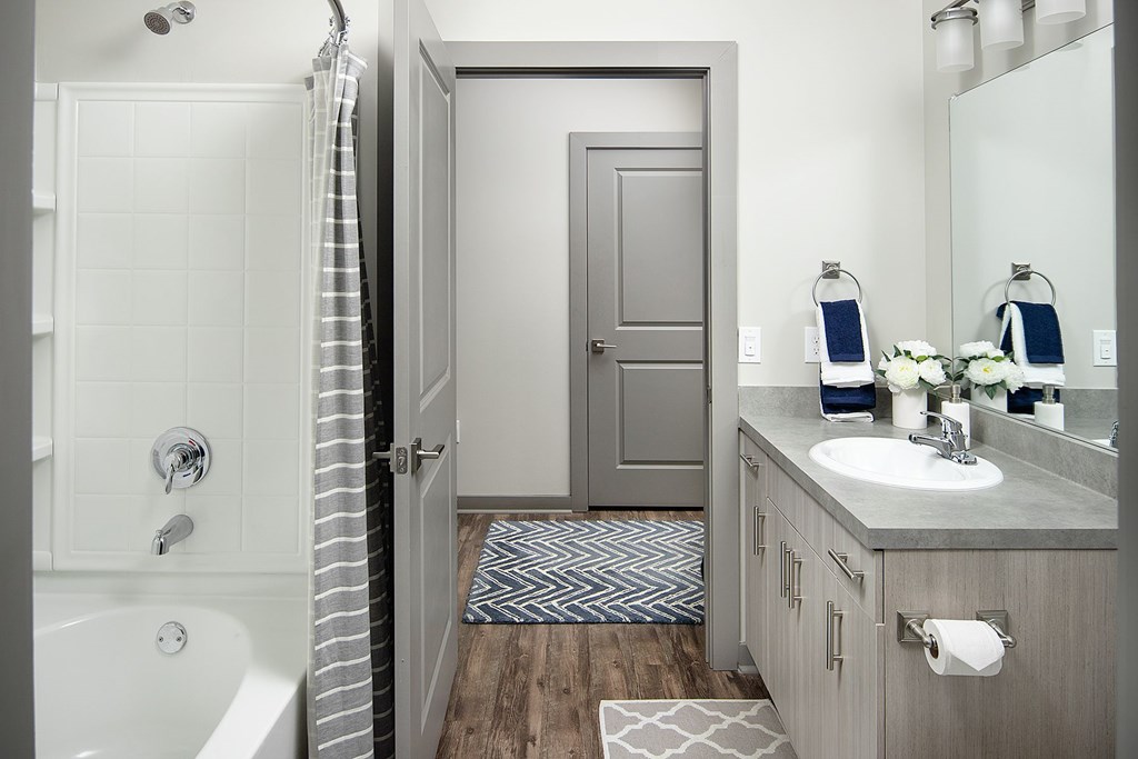 A bathroom with a white tub, sink, and a grey door.