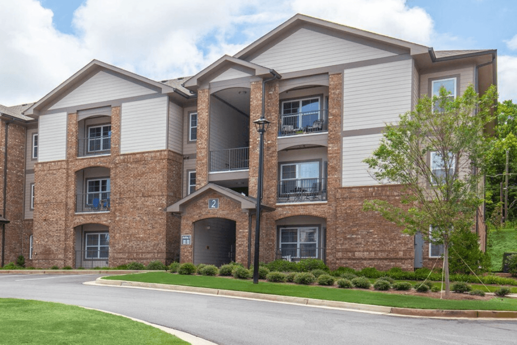A large brick building with a white roof and a tree in front.